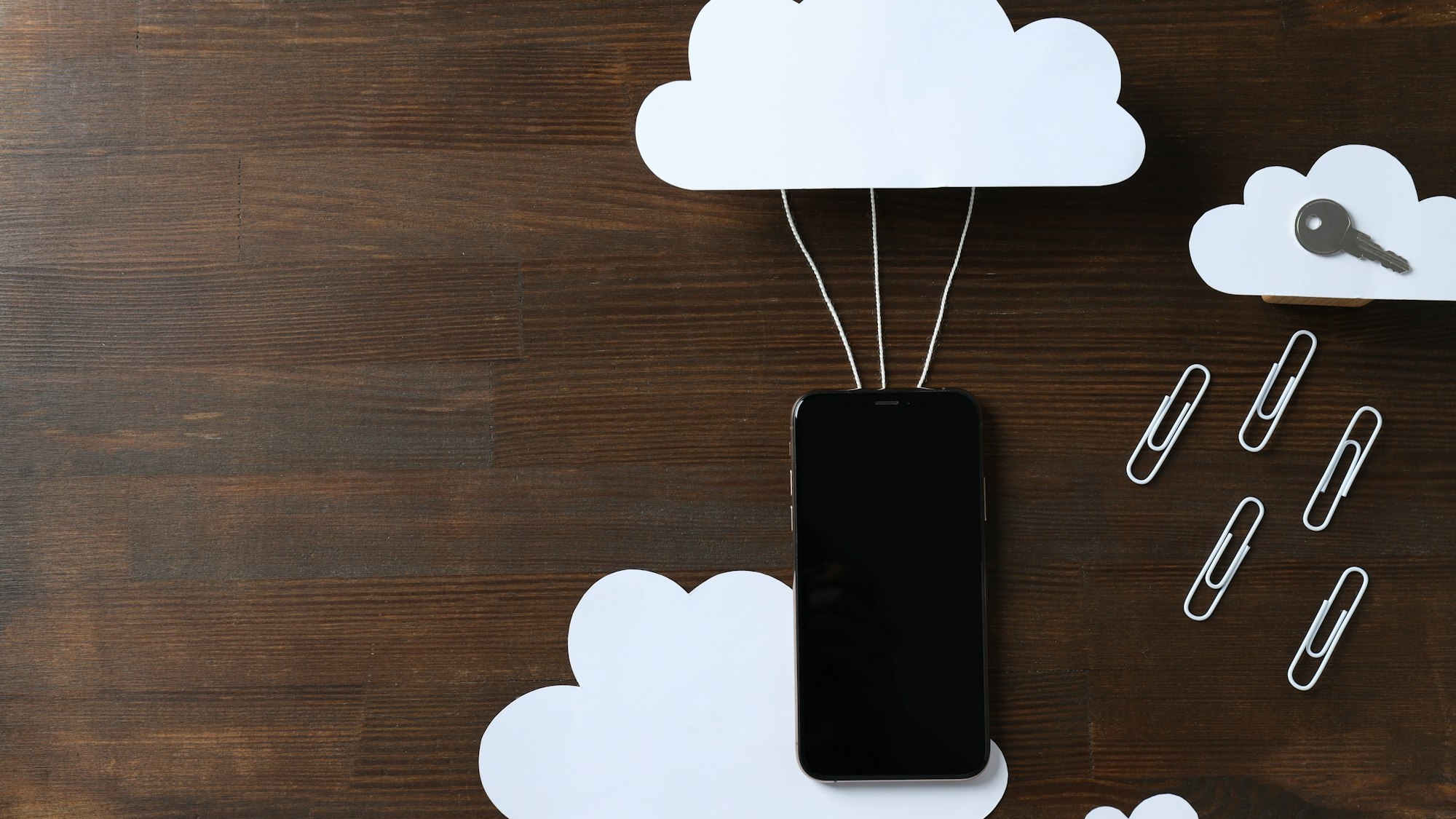 Black smartphone with a paper cloud on a dark background