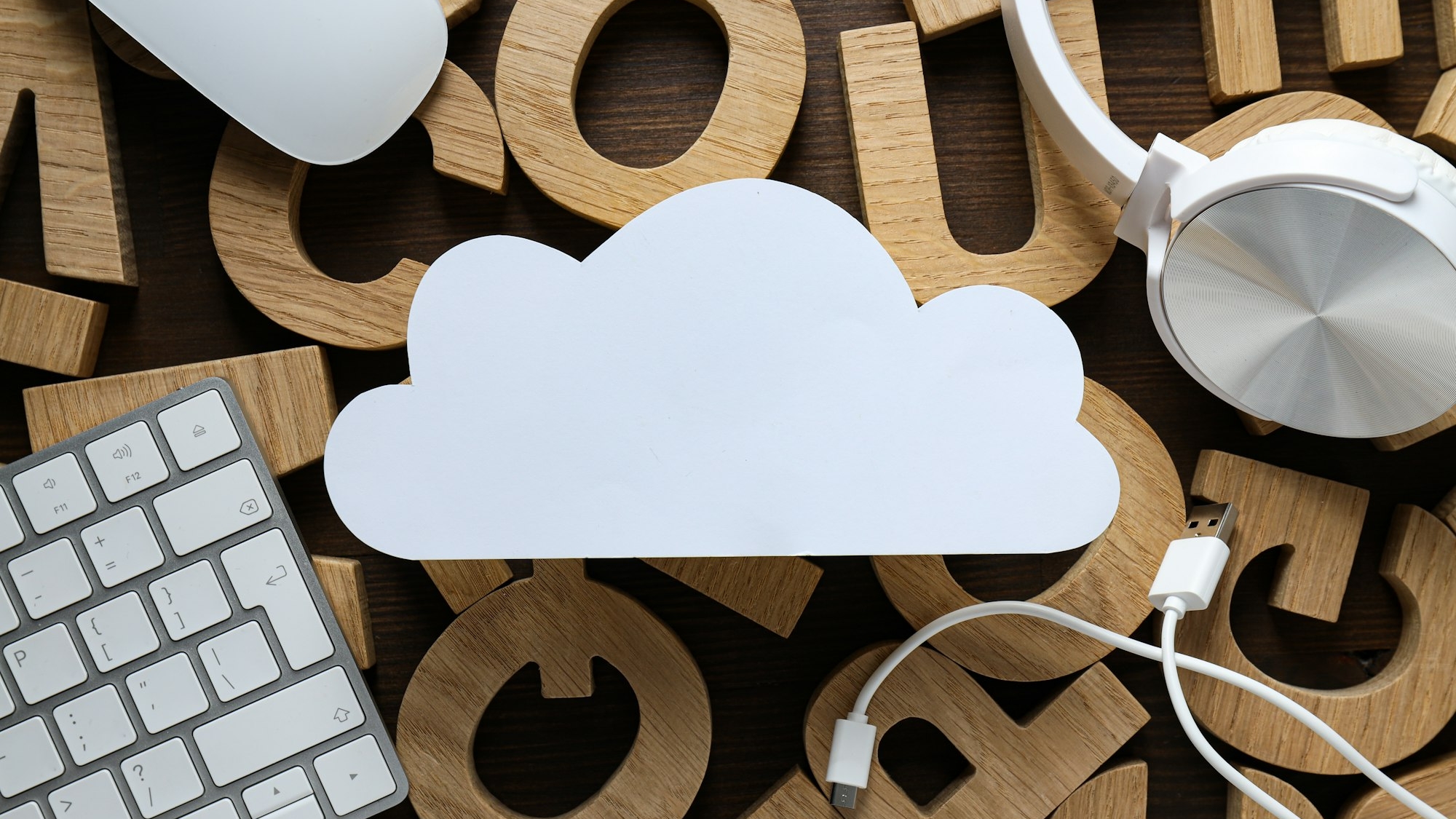 White, paper cloud with gadgets on the background of wooden letters, cloud computing concept