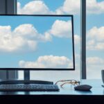 Conceptual cloud computing desk with computer, keyboard, mouse, eyeglasses and coffee.