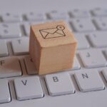 Wooden cube with new email notification icon on top of keyboard.