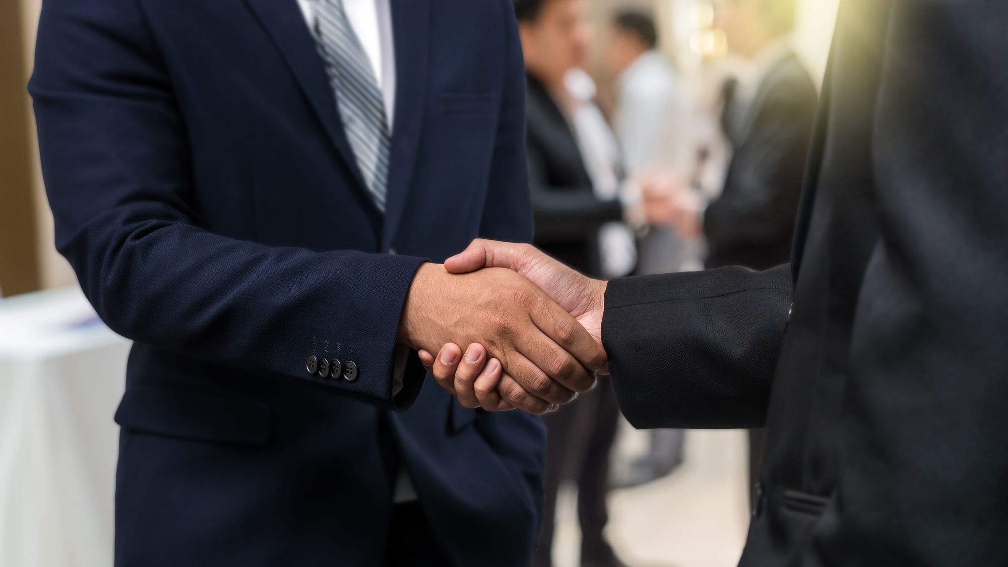 Business shaking hands of partner over the photo blurred of group of Businessman Corporate
