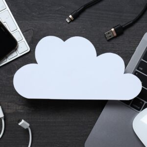 White, paper cloud with various gadgets on a black table background