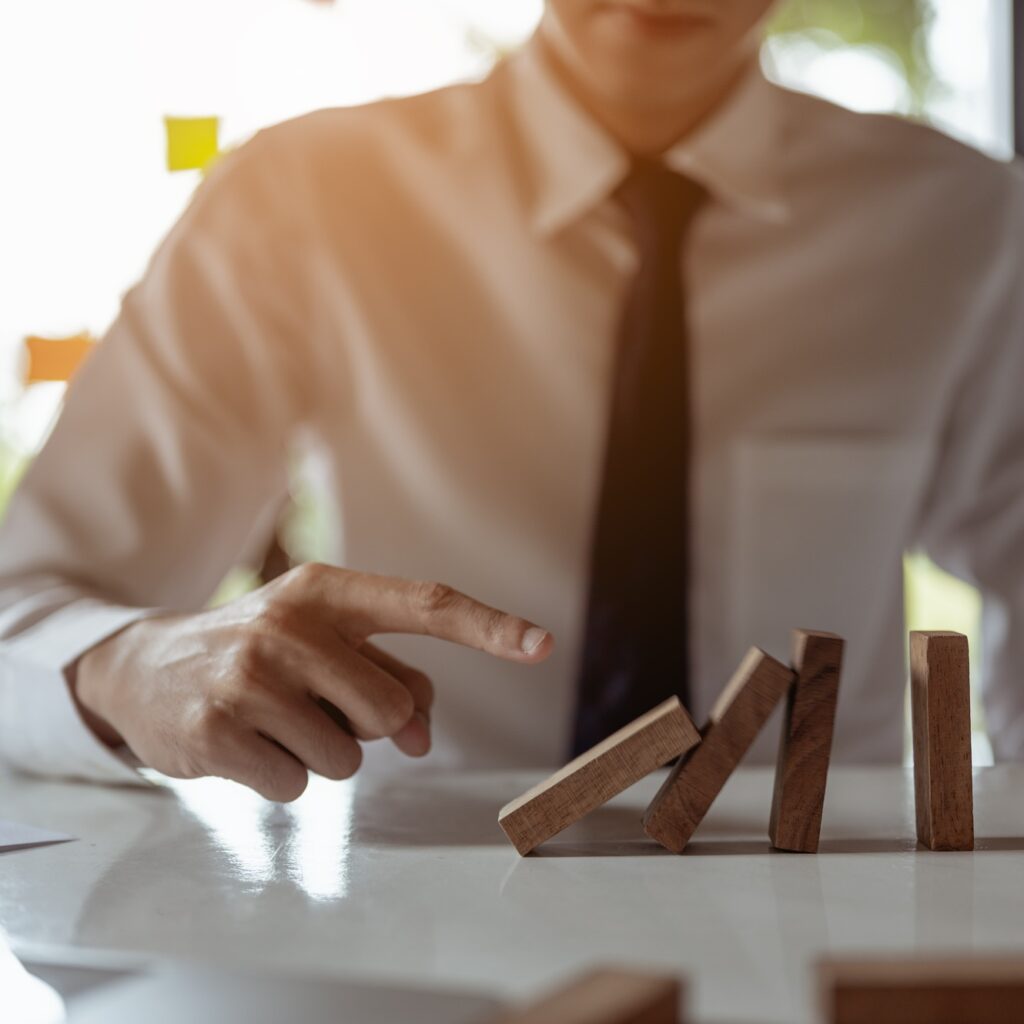 Businessman pulling or placing long wooden blocks in a modern office Indicates the impact