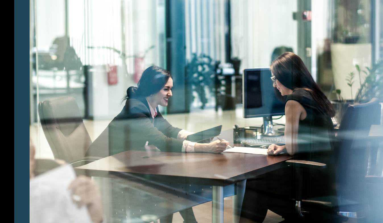 A Microsoft solution consultant from Altron Digital sitting at her desk across from her client during a meeting