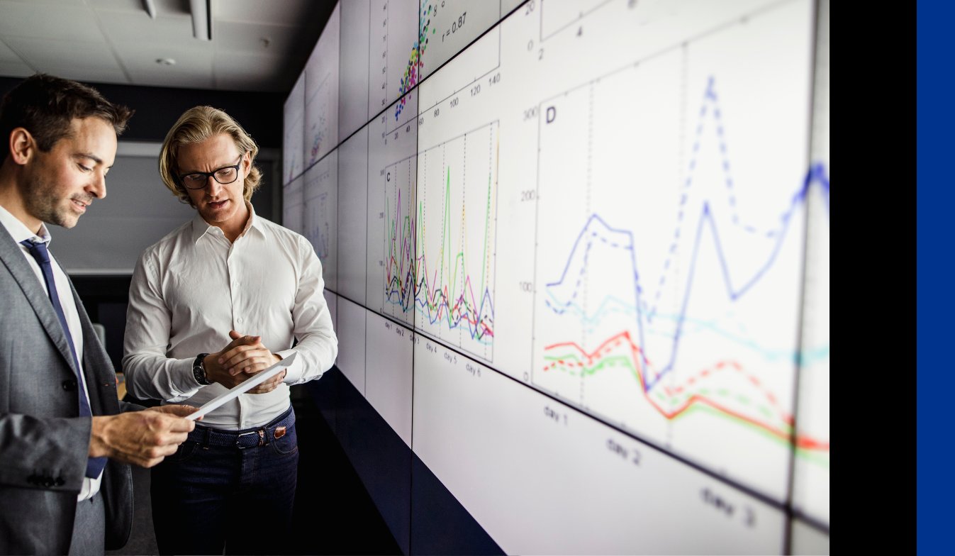KPMG data analysts working together and standing infront of a large screen with data