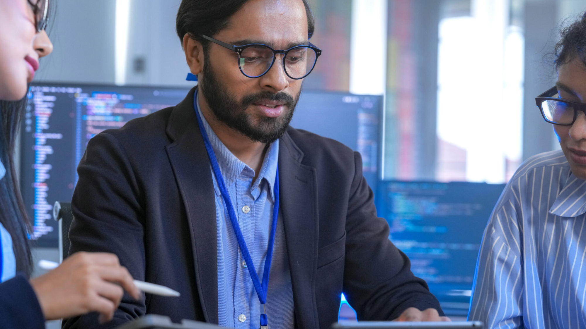 A senior tech lead or manager mentoring a diverse team of junior developers in a modern office. Concept for project management, corporate training, and professional growth.