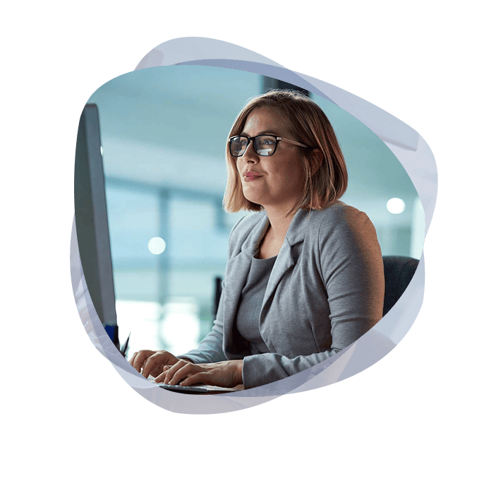 An employee, wearing glasses and a grey suit, working on her desktop with M365 Co-Pilot.
