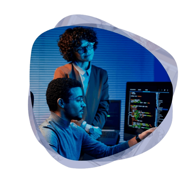 Two tech specialists reviewing code on a monitor while discussing Microsoft Agentic AI Development Services in a high-tech office.