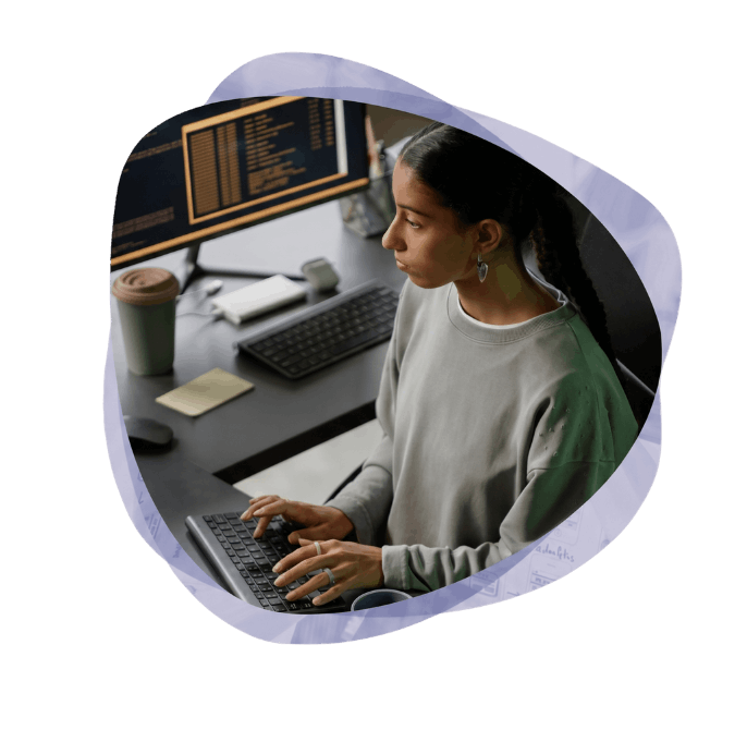 A female developer typing on a keyboard at a multi-monitor workstation, engaged in Azure cloud-native development.