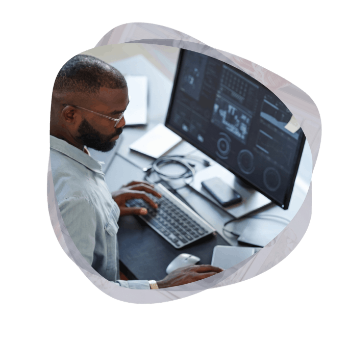 An IT professional wearing glasses and a blue shirt reviews dashboard analytics on a large monitor, conducting a Power Platform environment analysis to identify performance bottlenecks.