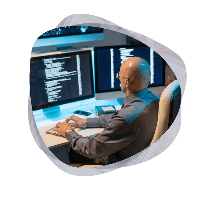 Developer executing application modernization work across two monitors displaying code.