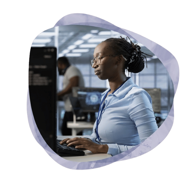 Alt text: A focused Mint Group engineer working at a computer in a modern operations centre, building out a Managed Evolution backlog in Azure DevOps for a client's Microsoft estate